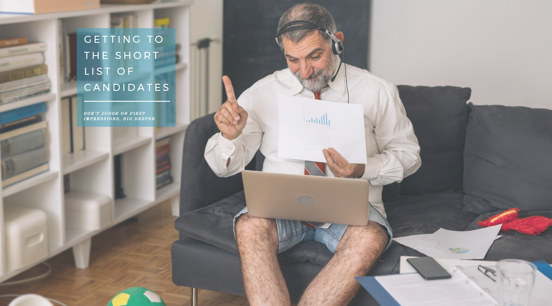 a man wearing shirt and tie presenting on his laptop from his sofa wearing denim shorts